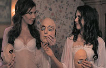 Gallery image from movie. Two girls in their bras holding creepy masks.